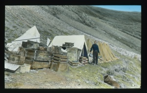 Image: Tents near Borup Lodge. A team member stands by large tent holding large pan....