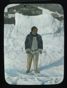 Image: Inuit woman standing by snow bank in front of Borup Lodge