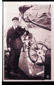 Image of Donald MacMillan standing by wheel, with arm around dog