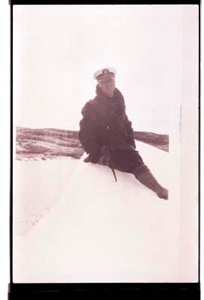 Image of Man sitting on snow or ice, with ice ax