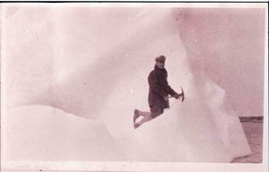 Image of Man kneeling on icy incline, holding pick axe