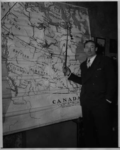 Image: Davis Irwin stands by map showing his planned route to the North Pole by dog sled in 1939 or 1940