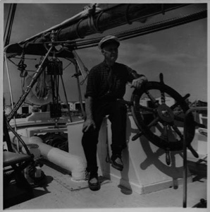 Image of Donald MacMillan sitting at the BOWDOIN's wheel, after arriving in Mystic Seaport