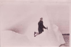 Image: Man kneeling on icy incline, holding pick axe