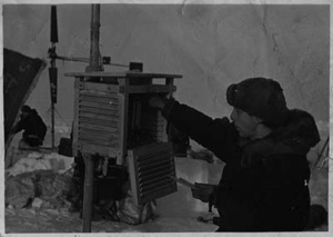 Image: Man reaches into instrument box. Holds a thermometer. Soviet Polar Expedition