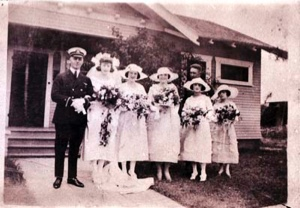 Image of Man in naval uniform stands beside five women holding flowers