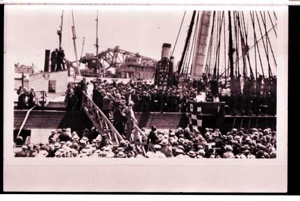 Image: Many people crowded onto pier, gangplank, ship. 