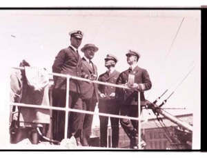 Image of Four men by upper rail of ship. Donald MacMillan on the right.
