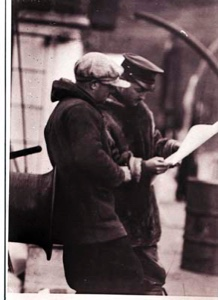 Image: Two men study a paper