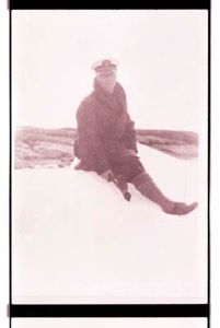 Image of Man, sitting on snow or ice with ice ax 
