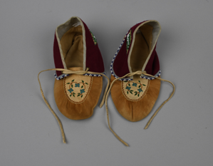 Image: pair of skin moccasins embroidered on vamp, with beaded cloth ankle-cuffs and skin ties a&b