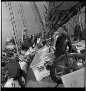 Image of "Shipwreck photos" - long view of  men, confusion on BOWDOIN's tilted deck. Pilot Peter Peterson sitting