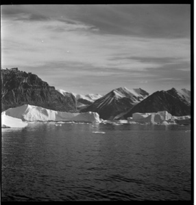 Image: Several icebergs by snow-capped mountains