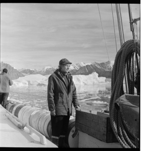 Image: Miriam standing on deck, large low iceberg  near