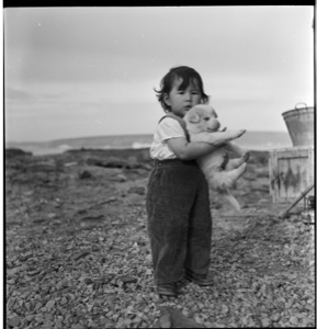 Image of Young Eskimo [Inuk] boy holding puppy