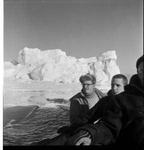 Image: Three crewmen sitting by rail, iceberg beyond. Tiger Burch in center