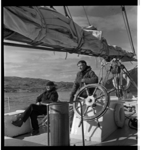 Image: MacMillan sitting on deck, Miriam at wheel