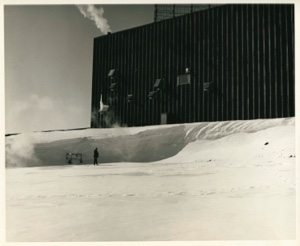 Image of Man standing by cart, near snow bank and building