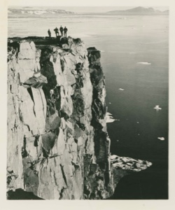 Image of Four men on extremely high cliff near BMEWS site, Thule AFB