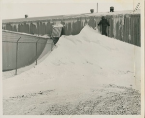Image: Man standing on snow pile near long building at Thule AFB