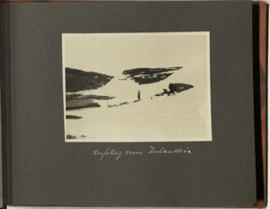 Image: Aufstieg zum Inlandeis [Ascent to the Inland Ice: on snowy hillside one man stands by three loaded sledges; two more men sit on snow by tent and equipment]