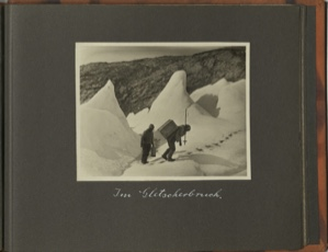 Image: Im Gletscherbruch [In the glacier breach?: [Two men follow foot-prints up the glacier. One carries large box on his back]