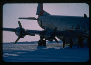 Image of c-124 incident. Figures standing by U.S. Airforce Troop Carrier on snow covered runway.