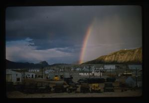 Image of Rainbow in the sky over a camp of small buildings.