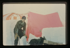 Image of Man in snow gear standing in front of tents.