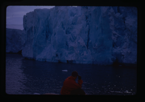 Image of Man in boat looking at glacier