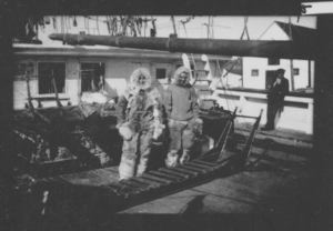 Image of MacMillan and George Borup on deck in furs, with sledge