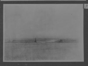 Image of Masts of the Roosevelt seen across snow field, sledge tracks in foreground