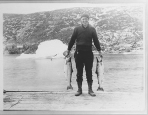 Image of Man wearing cap, holding two large fish