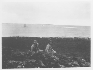 Image of [Two men sitting near shore, Bowdoin in distance]