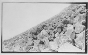 Image of [Eskimo [Inuk] woman sitting on a rocky slope]