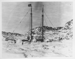 Image of Bowdoin frozen in Refuge Harbor [Qamarfit]. Flag flying for Peary, April, 1924