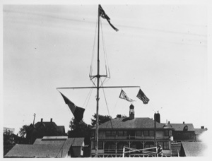 Image of [Flags on mast (Chicago Yacht Club pennant); building beyond]