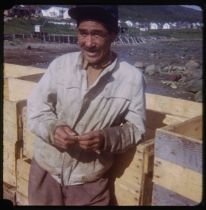 Image of Eskimo [Inuk] man leaning on crates