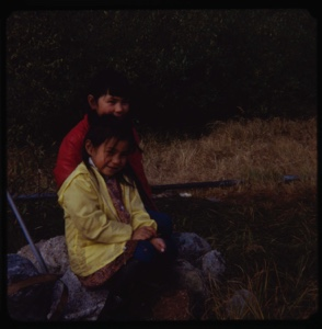 Image of Two Eskimo [Inuit] girls sitting on a rock