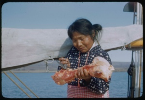 Image of Inawahoo cutting meat with ooloo, on Bowdoin