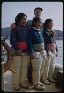 Image of Donald MacMillan and three women from NP Expedition, showing thigh-high boots