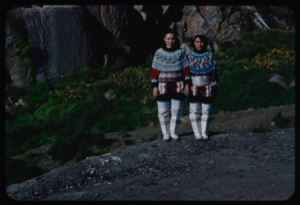 Image: Two Eskimo [Inuit] women in traditional dress, by wildflowers