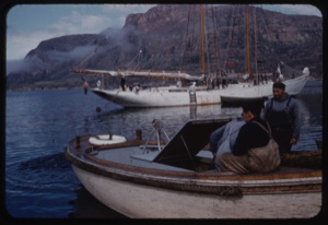 Image of Bowdoin near open boats. Donald MacMillan at stern