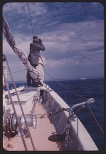Image of Donald MacMillan [?] standing at bow, spotting first iceberg