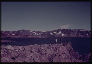 Image of Two people on rocks looking to coastal mountains