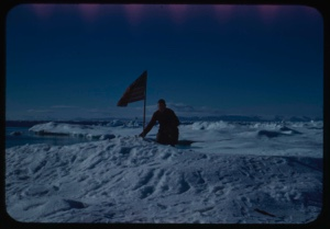 Image of Peter Rand kneeling with flag at farthest north