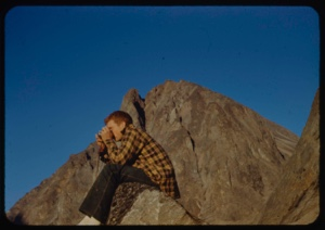 Image of Roger Cromwell sitting on rock with camera
