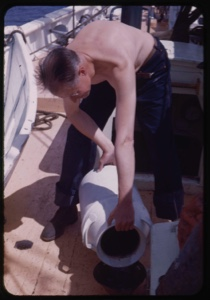 Image of Crewman on deck with water can