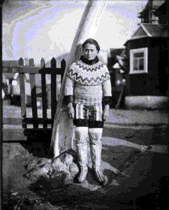 Image of Eskimo [Inuk] woman in dress-costume by church