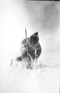 Image of Inuit at seal hole in ice